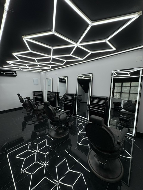 A barber shop interior featuring striking black and white lighting, creating a classic and stylish atmosphere.