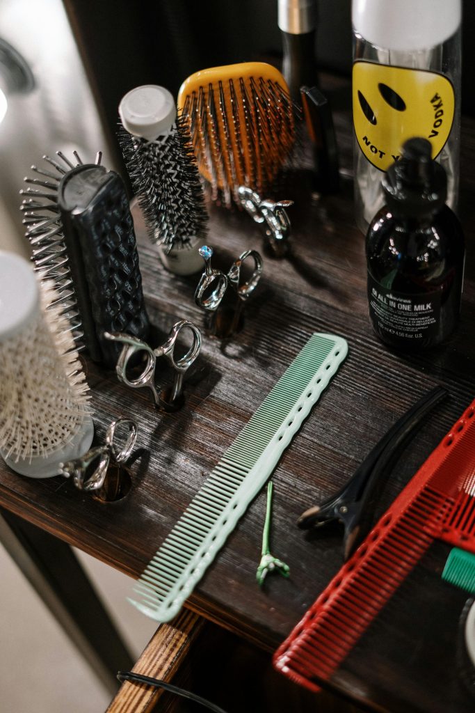 Close-up of diverse barber tools and styling products arranged on a wooden table in a salon.